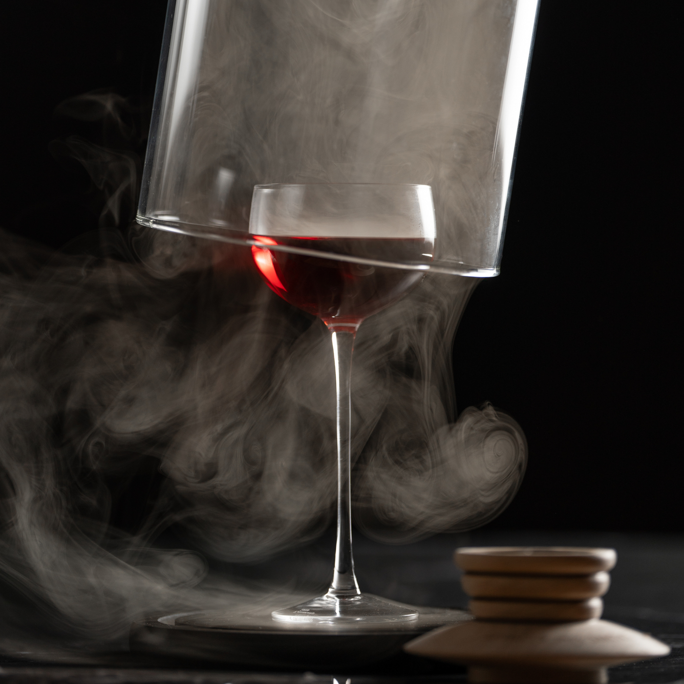 Smoked glass and manhattan cocktail with glass cloche being lifted